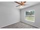 Bedroom featuring gray carpet, a ceiling fan, and a window providing natural light at 7139 Se 122Nd Ln, Belleview, FL 34420