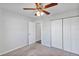 Neutral bedroom with grey carpeting, ceiling fan, and closet doors at 7139 Se 122Nd Ln, Belleview, FL 34420