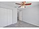 Bedroom with a ceiling fan, gray carpet, closet, and doorway leading to another room at 7139 Se 122Nd Ln, Belleview, FL 34420