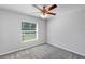 Bedroom featuring gray carpet, a ceiling fan, and a window providing natural light at 7139 Se 122Nd Ln, Belleview, FL 34420