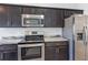 Close-up of stainless steel oven and microwave with dark wood cabinetry and granite countertops at 7139 Se 122Nd Ln, Belleview, FL 34420