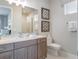 Bathroom featuring a double sink vanity with marble countertop, toilet, and tiled shower at 985 Jack Nicklaus Ct, Kissimmee, FL 34747