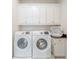 Laundry room equipped with white washer, dryer and overhead cabinets at 985 Jack Nicklaus Ct, Kissimmee, FL 34747