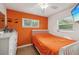 Cozy bedroom with bright orange accent wall, white furniture, and natural light at 1004 Sunwood Lane Ln, Orlando, FL 32807