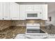 Kitchen featuring white cabinets, speckled granite countertops, mosaic backsplash, and modern appliances at 1004 Sunwood Lane Ln, Orlando, FL 32807