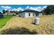 Image of the back of a gray house under a blue sky and bright grass, with a water tank visible at 11 Spruce Ln, Ocala, FL 34472