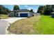 Charming single-story home showcasing a well-manicured lawn and a blue two-car garage at 11 Spruce Ln, Ocala, FL 34472