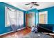 An interior view of a blue bedroom with hardwood floors and a ceiling fan at 1213 Cr 652, Bushnell, FL 33513