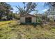 A small plywood shed or outbuilding on a grassy lot surrounded by trees and a chain-link fence at 1213 Cr 652, Bushnell, FL 33513