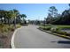 View of a neighborhood gate surrounded by palm trees and greenery, offering security and a welcoming entrance at 17826 Blazing Star Cir, Clermont, FL 34714