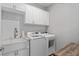 Laundry room with white cabinets, tile backsplash, stainless sink and modern washer/dryer at 17826 Blazing Star Cir, Clermont, FL 34714