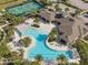 Aerial view of the community pool area with palm trees, lounge chairs, tennis courts, and clubhouse at 17826 Blazing Star Cir, Clermont, FL 34714