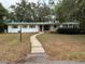 Single-story home with a green roof and a curved sidewalk leading to the front door at 22 Poinsettia Dr, Deland, FL 32724