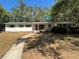 Charming single-story home with a walkway leading to the front door and mature trees at 22 Poinsettia Dr, Deland, FL 32724
