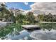 Picturesque view of a clear pond with a floating dock, framed by lush trees and a cloudy sky at 229 Springside Rd, Longwood, FL 32779