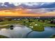 Aerial view of a golf course at sunset, showcasing the lush green landscape, water features, and surrounding property at 314 Muirfield Loop, Reunion, FL 34747