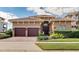 Elegant home featuring a tile roof, symmetrical landscaping, and a two-car garage on a sunny day at 314 Muirfield Loop, Reunion, FL 34747