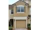 Two-story townhome featuring a tan exterior, private garage, and well-maintained landscaping at 3401 Shallot Dr # 107, Orlando, FL 32835