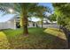 Lush backyard featuring palm trees, green lawn, white fence and covered patio at 43 Pergola Pl, Ormond Beach, FL 32174