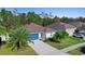 Well-maintained single-story home featuring mature landscaping, blue garage door, and a concrete driveway at 43 Pergola Pl, Ormond Beach, FL 32174