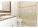 Bathroom with a marble countertop vanity, mirror, toilet, and a bathtub with beige tiling at 500 Pickfair Ter, Lake Mary, FL 32746