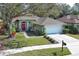 Charming home with a well-manicured lawn, flowering plants, and a red front door at 500 Pickfair Ter, Lake Mary, FL 32746