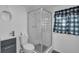 Bathroom features a glass shower, modern fixtures, a toilet, and a window with a curtain at 513 Wisconsin Ave, St Cloud, FL 34769