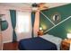 Cozy bedroom with a modern green accent wall, ceiling fan, and two nightstands at 5521 Rutherford Pl, Oviedo, FL 32765