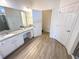 Bathroom showcases a double sink vanity with a granite countertop, white cabinets, and wood-look tile flooring at 6004 Oak Green Loop, Davenport, FL 33837