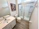 Bright bathroom features glass shower doors, a framed art piece, wood look tile flooring, and a white vanity at 6004 Oak Green Loop, Davenport, FL 33837