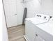 Bright laundry room with modern washer and dryer, ironing board, and ample space for laundry tasks at 6004 Oak Green Loop, Davenport, FL 33837