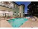 A backyard pool at dusk, featuring submerged loungers, an outdoor shower, and patio with a ping pong table at 7465 Gathering Loop, Reunion, FL 34747