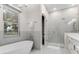 Well-lit bathroom featuring a modern tub, window, separate glassed shower and double vanity with sleek fixtures at 7465 Gathering Loop, Reunion, FL 34747