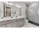 Modern bathroom with dual sinks, gray cabinets, and decorative tile in the walk-in shower at 7465 Gathering Loop, Reunion, FL 34747