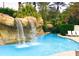 Beautiful pool area with lush tropical landscaping and waterfall feature at 7465 Gathering Loop, Reunion, FL 34747