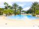 Resort pool with beach entry, surrounded by palm trees, lounge chairs and tropical foliage at 7465 Gathering Loop, Reunion, FL 34747