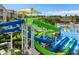 Aerial view of the pool with a yellow sunshade, waterslides, a splashpad, and lush greenery at 7671 Otterspool St, Kissimmee, FL 34747