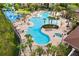 Aerial view of the pool with a beach entry, ample seating, shade, lush palm trees, a waterslide, and a splash pad at 7671 Otterspool St, Kissimmee, FL 34747