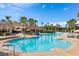 View of the resort style pool with ample seating and umbrellas, lush landscaping, and a nearby recreation area at 7671 Otterspool St, Kissimmee, FL 34747