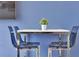 Dining area features modern table with chrome legs, and four blue acrylic chairs against a blue wall at 7671 Otterspool St, Kissimmee, FL 34747