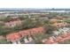 An aerial view shows the community, with red tile roofs, mature trees, and a view of the city in the background at 7709 Sundial Ln, Orlando, FL 32819