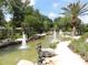 A tranquil water fountain with multiple spouts and a statue of a , surrounded by lush greenery and walking paths at 7709 Sundial Ln, Orlando, FL 32819