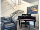 Cozy living room featuring a black piano and a leather chair under the staircase at 7709 Sundial Ln, Orlando, FL 32819