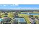 Stunning aerial shot of tennis courts, lake with fountain, and surrounding greenery at 8044 Saint James Way, Mount Dora, FL 32757