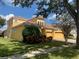 Stylish yellow two-story home with lush green lawns and colorful landscaping on a sunny day at 8908 Via Bella Notte, Orlando, FL 32836