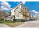 View of townhomes with tan and white exteriors, manicured bushes, private garages, and brick-paved driveway and walkways at 11 W Harding St # D, Orlando, FL 32806