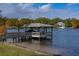 Lakeside dock with boat lift shows beautiful home in the background and grassy shoreline at 1100 S Lake Sybelia Dr, Maitland, FL 32751