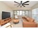 Bright living room with a large ceiling fan, light wood floors, and modern furniture arrangement at 117 Shannon Dr, Sanford, FL 32773