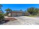 Three-car garage featuring brick accents and a large concrete driveway, adding to the home's curb appeal at 1303 Sultan Cir, Chuluota, FL 32766