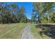 Stunning lake view featuring a paved walkway leading to a seating area, surrounded by lush trees and greenery at 1303 Sultan Cir, Chuluota, FL 32766